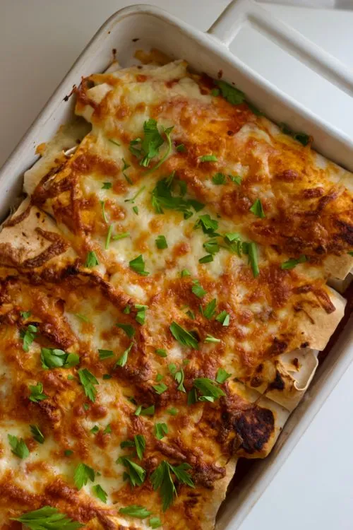 Cheesy baked enchiladas garnished with fresh herbs