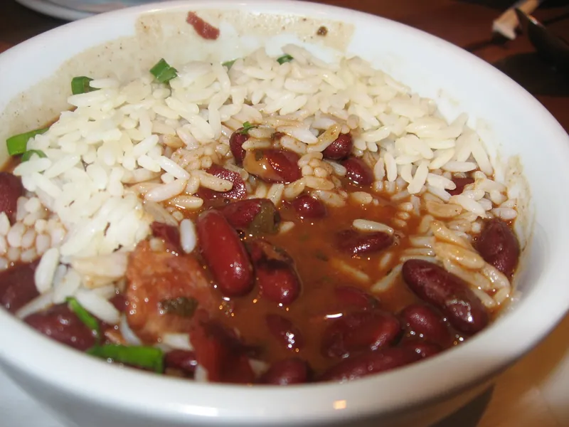Bowl of creamy Louisiana-style red kidney beans with smoked sausage, scallions and white rice