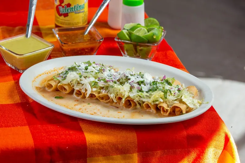 Crispy rolled tacos served with dipping sauces and lime