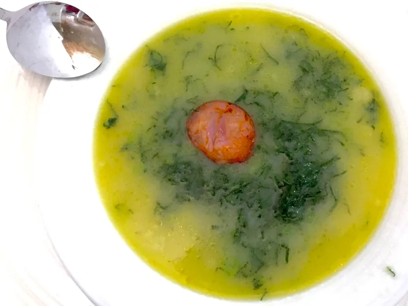Portuguese caldo verde potato soup with shredded kale and a round slice of sausage