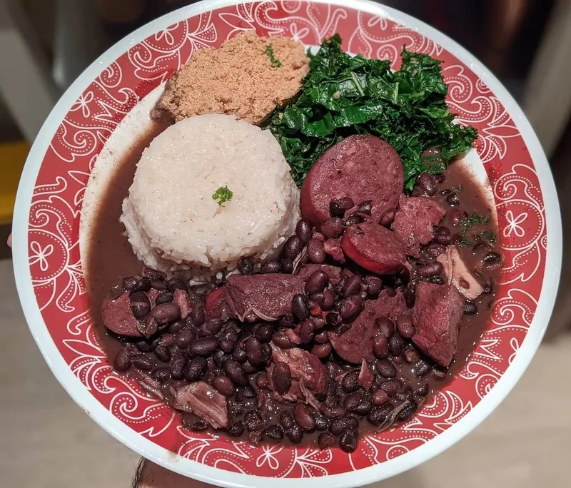 Brazilian-style feijoada with black beans, pork and sliced sausage served with white rice, collard greens and farofa
