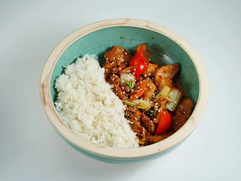 Sesame chicken and vegetables served beside steamed rice