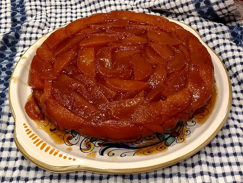 Whole French tarte Tatin with glossy deeply caramelized apple wedges arranged over a round pastry base