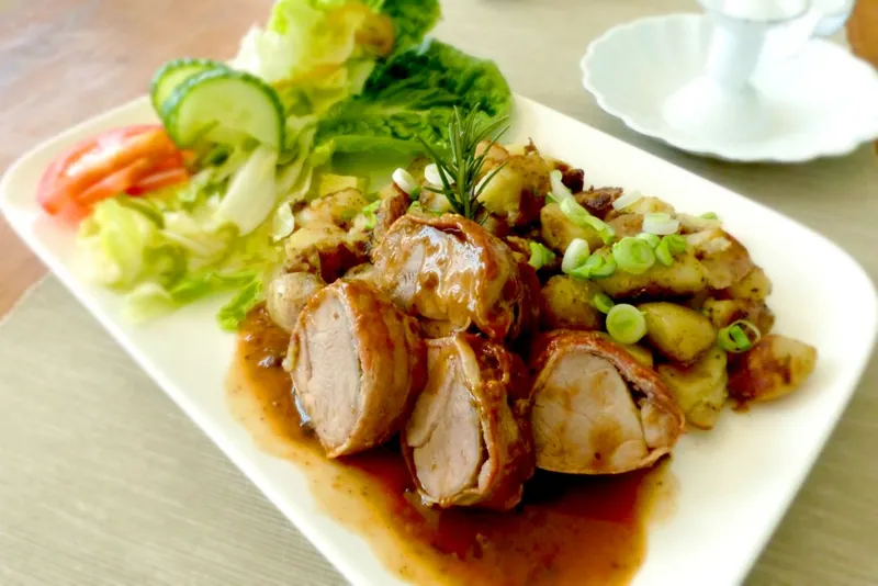 Sliced roasted pork tenderloin with potatoes and green vegetables