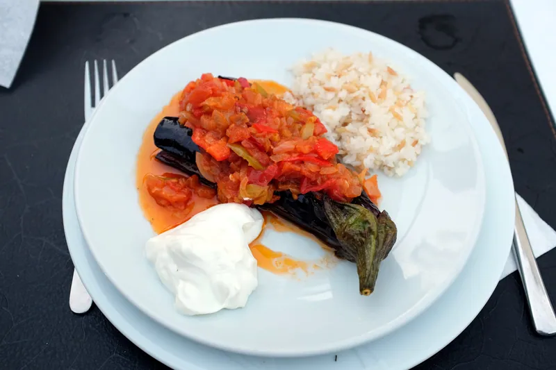 Baked whole eggplant filled with tomato and onion, served with white rice and yogurt