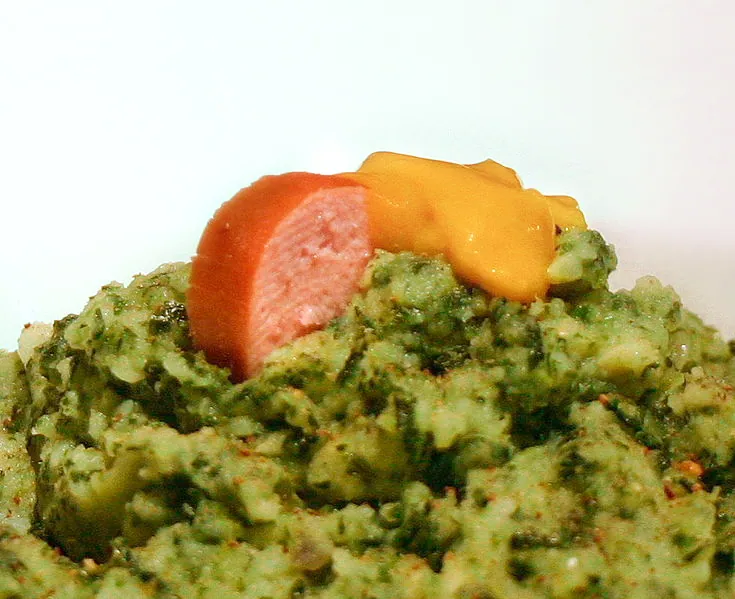 Dutch kale and potato stamppot topped with sliced smoked sausage and yellow mustard