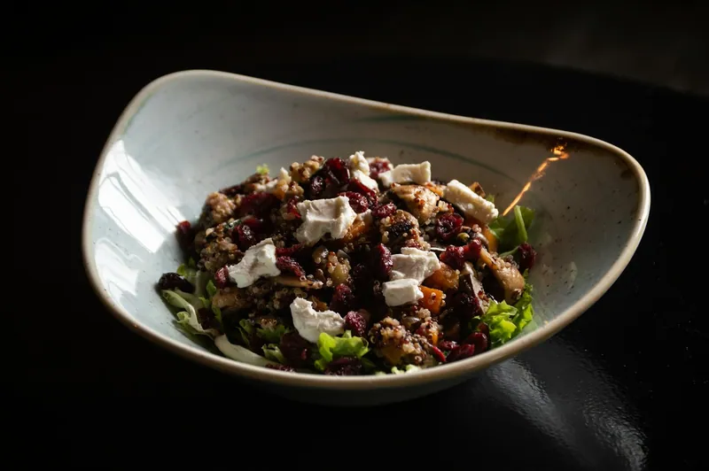 Warm quinoa salad with butternut squash, browned mushrooms, dried cranberries, feta chunks, and tender green leaves