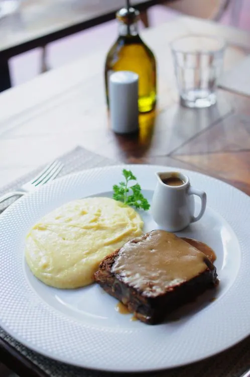Slices of glazed beef meatloaf served with creamy mashed potatoes, brown gravy, and parsley