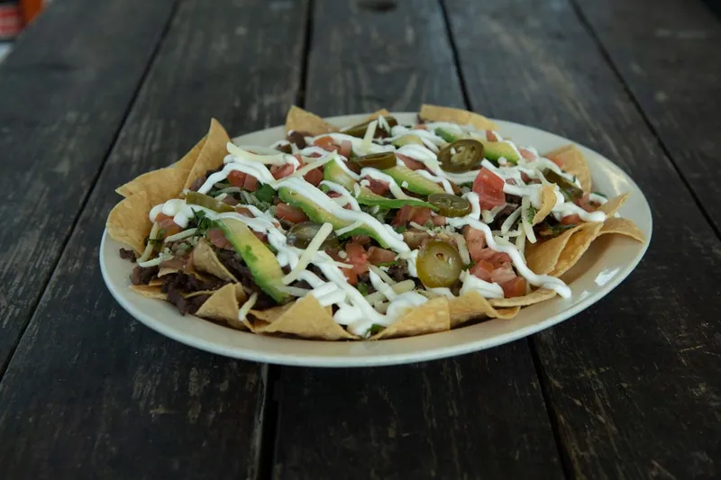 Cheesy beef nachos with tortilla chips, guacamole, jalapeños, and sour cream