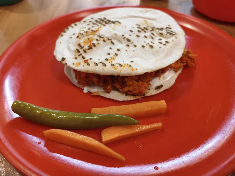 Chopped chicken shawarma and creamy sauce stuffed between two toasted pita rounds with pickled vegetables