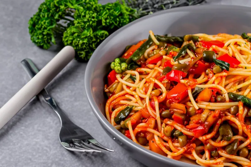 Long pasta tossed with colorful peppers and green vegetables