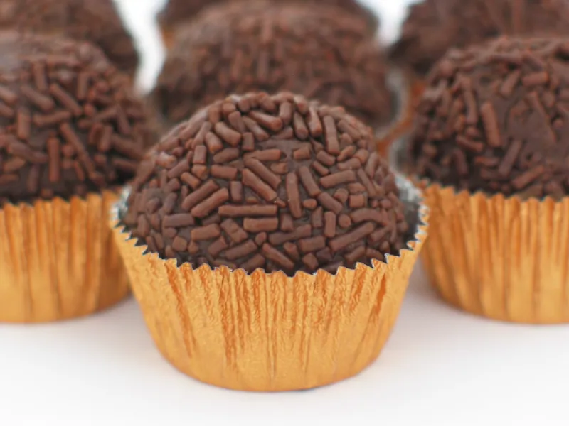 Round Brazilian chocolate brigadeiros coated in chocolate sprinkles and arranged in gold paper cups