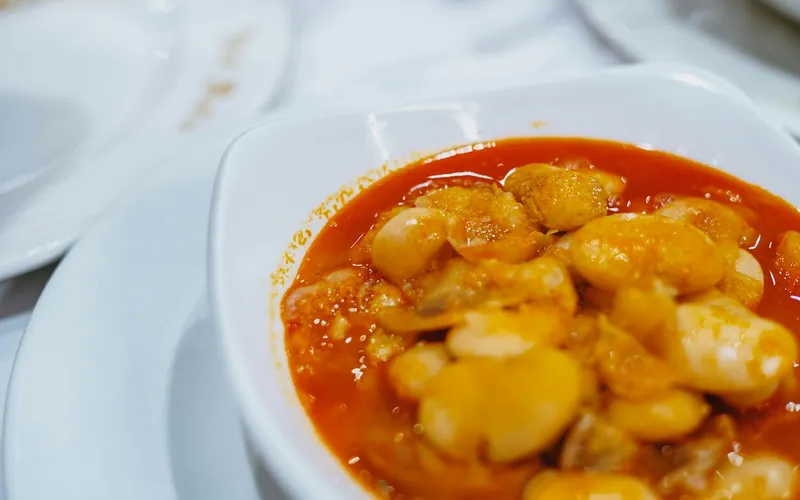 Large white butter beans in a glossy red tomato sauce served in a white bowl