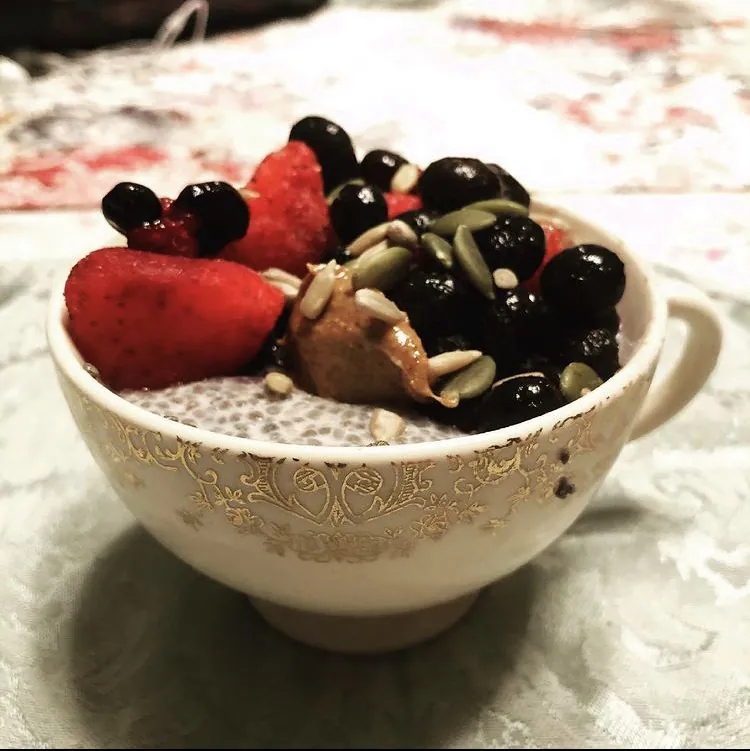 Creamy chia pudding cup topped with strawberries, blueberries, almond butter, pumpkin seeds and sunflower seeds