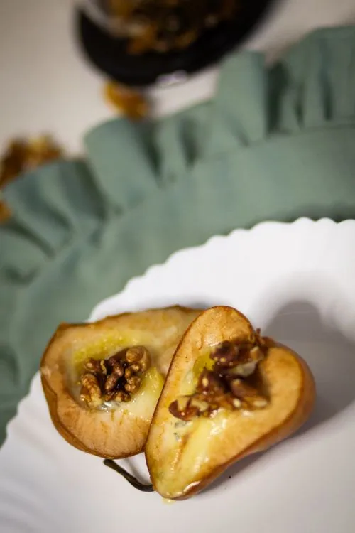 Two golden baked pear halves filled with walnuts and glazed with honey on a white plate