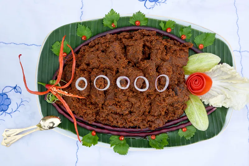Dark, dry Indonesian beef rendang coated with toasted coconut and spices on a banana-leaf-lined platter
