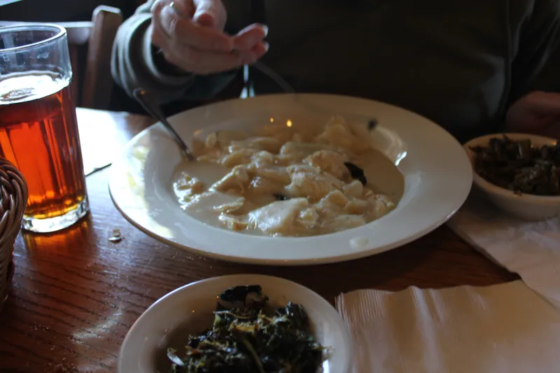 Southern chicken and flat dumplings in a pale creamy broth served in a wide white bowl