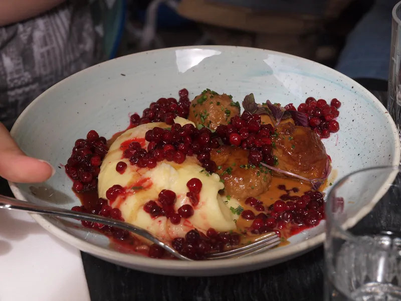 Swedish-style browned meatballs with cream gravy, mashed potatoes and bright lingonberries on a white plate