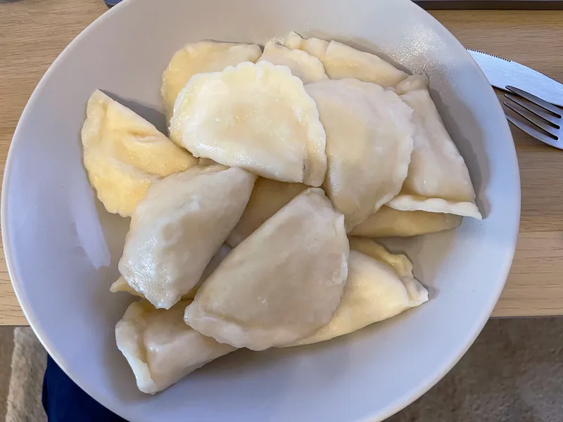 Bowl of boiled Polish pierogi filled with potato, cheese and onion