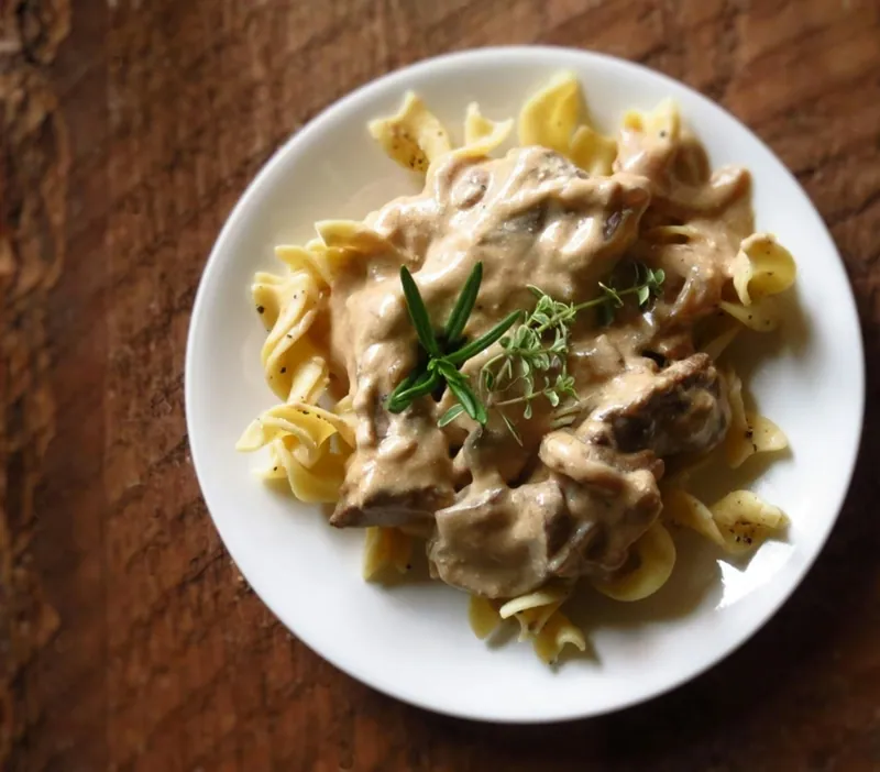 Creamy beef stroganoff served over wide egg noodles and garnished with fresh parsley
