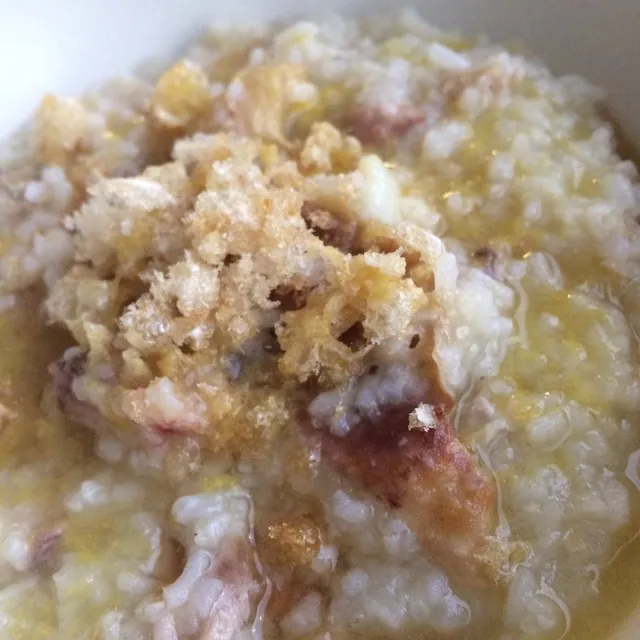 Bowl of Filipino chicken arroz caldo with visible chicken pieces in thick rice porridge