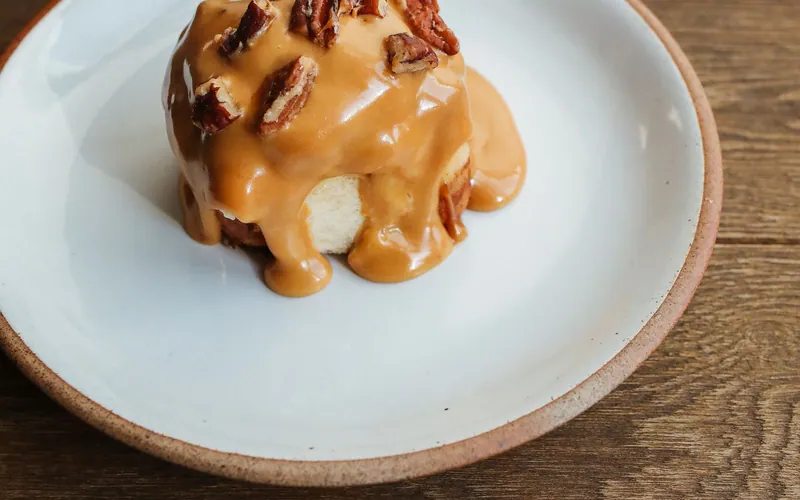 Individual sticky toffee pudding covered in thick golden toffee sauce and topped with chopped toasted pecans