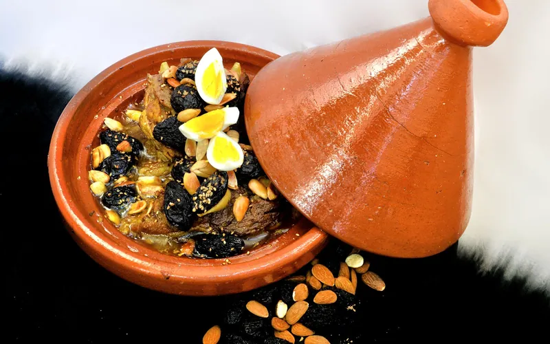 Clay tagine filled with browned lamb, glossy black prunes, toasted almonds, sesame seeds and quartered hard-cooked quail eggs