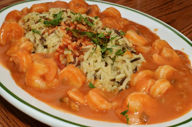 Platter of shrimp in orange-brown étouffée gravy surrounding parsley-flecked long-grain and wild-rice pilaf