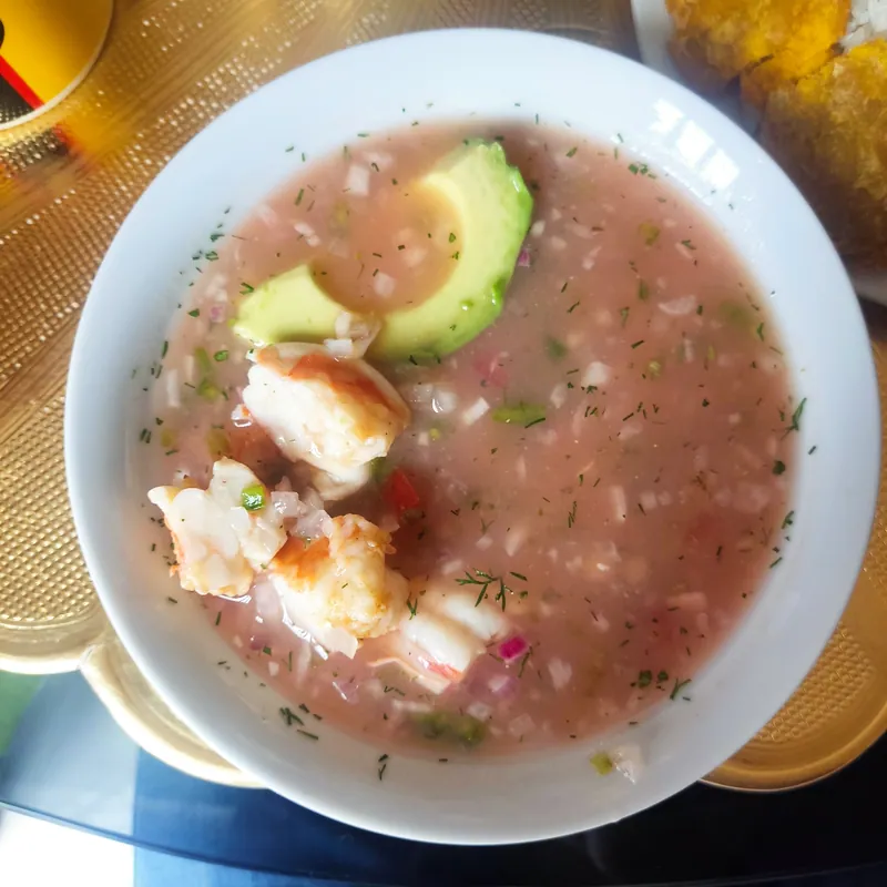 Ecuadorian-style shrimp ceviche in a pale pink tomato-lime broth with red onion, herbs and avocado slices